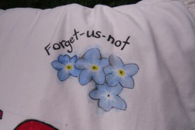 Forget us not written on a white pillowcase with blue flowers