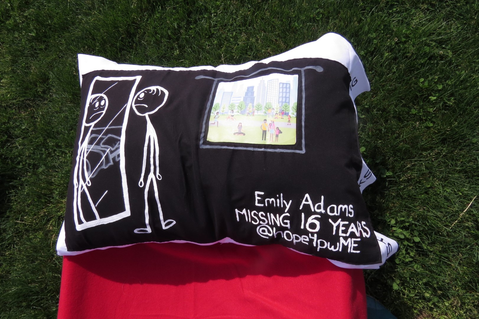 A black pillowcase with a stick figure looking into a mirror with an open window in the background